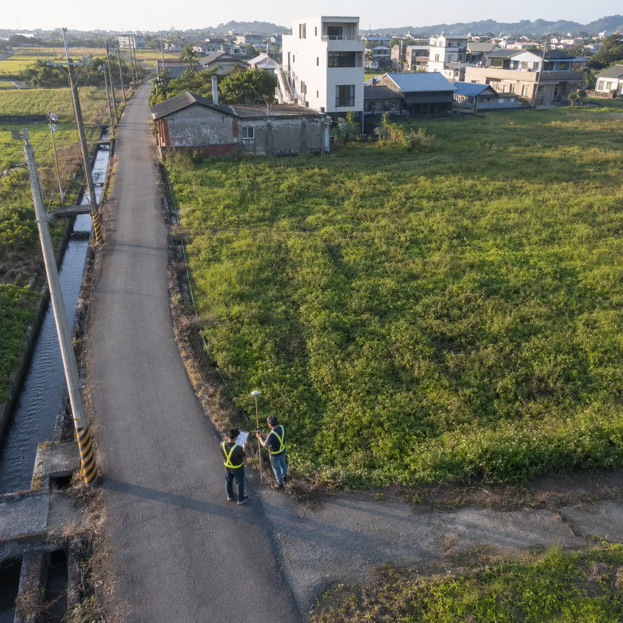 台灣鄉間既有道路通過土地旁,測量人員現場確認道路與基地關係