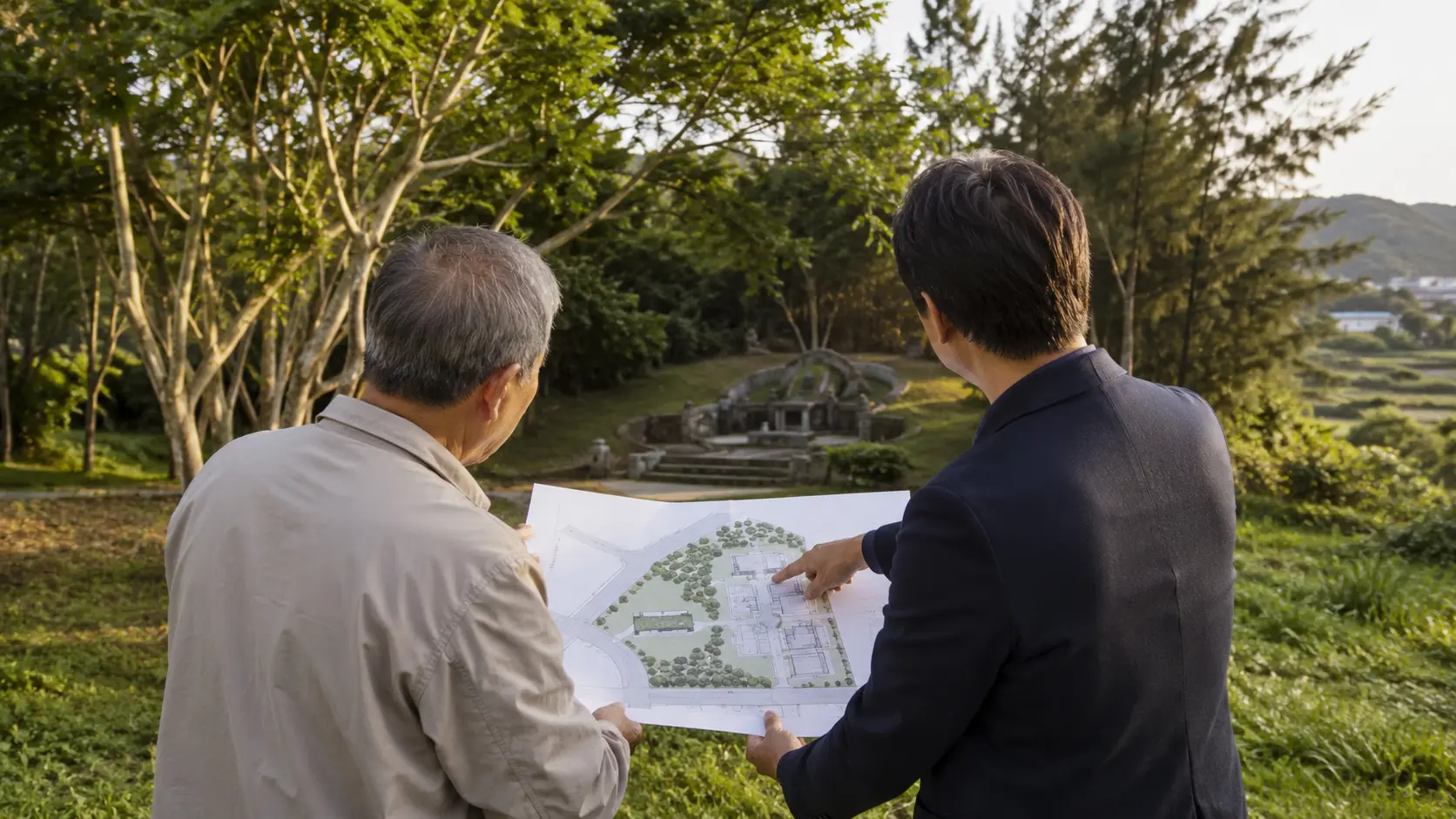 地主與土地顧問在家族墓地旁檢視保留綠地與基地配置圖